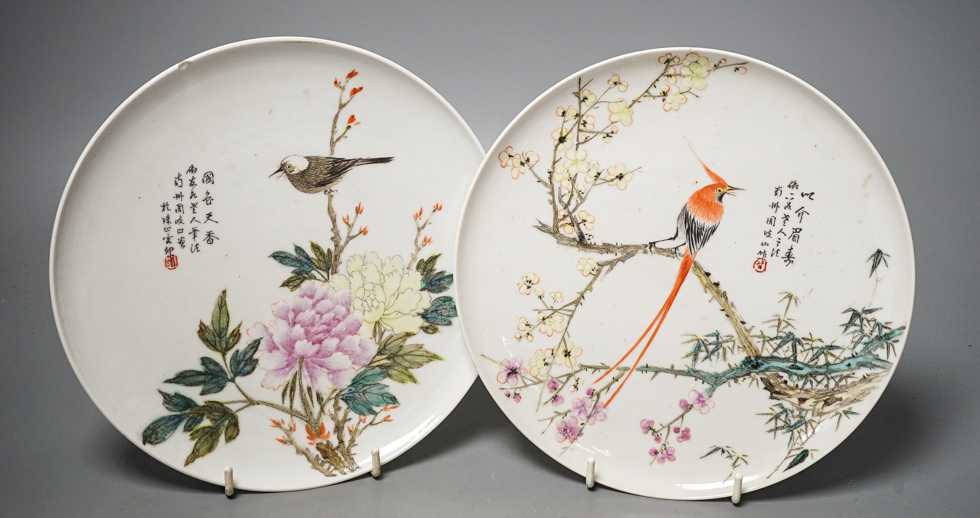 A pair of Chinese famille rose dishes, Qianlong marks possibly Republic period, each painted with a bird perched amid prunus and bamboo or red blossom and peonies, inscribed, D. 22cm